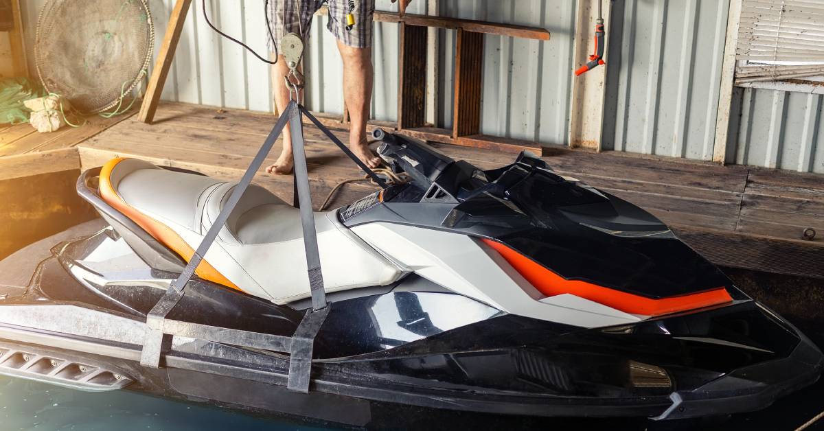 A man is standing on a wooden dock and using a handheld device to lift a black and white jet ski out of the water. A man is standing on a wooden dock and using a handheld device to lift a black and white jet ski out of the water.